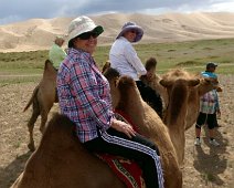 C017_Camels Sylvia, Joyce and Kenn off on a camel ride. Bactrian camels have two humps rather than the single hump of their Arabian relatives. The humps function the same...